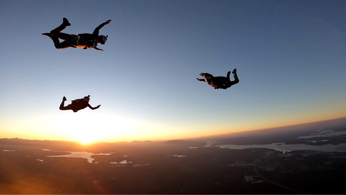 Sunset with silhouette of 3 skydivers